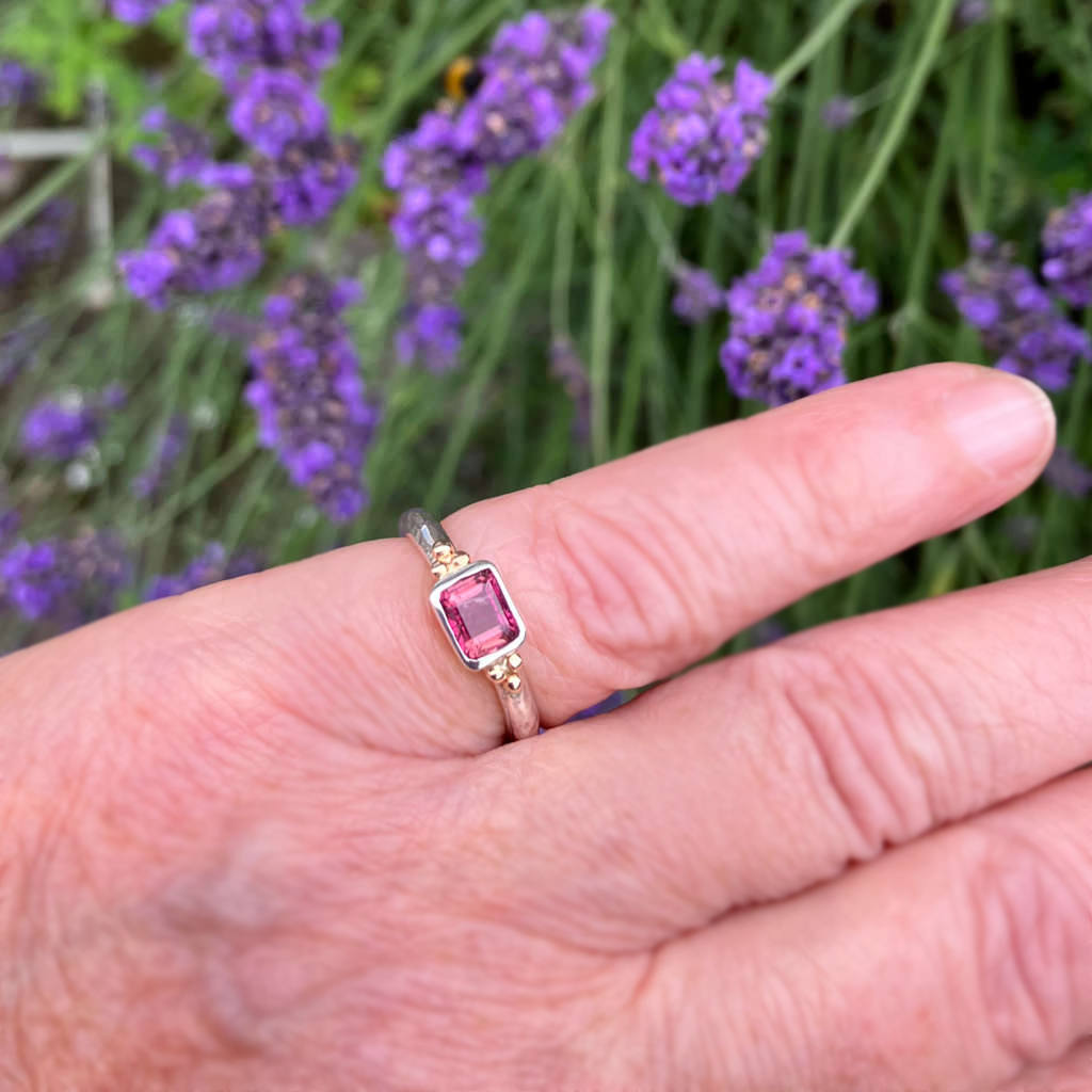 Hand wearing a silver ring with a pink tourmline gemstone and 9ct gold granule Amanda Cox for Heart Gallery