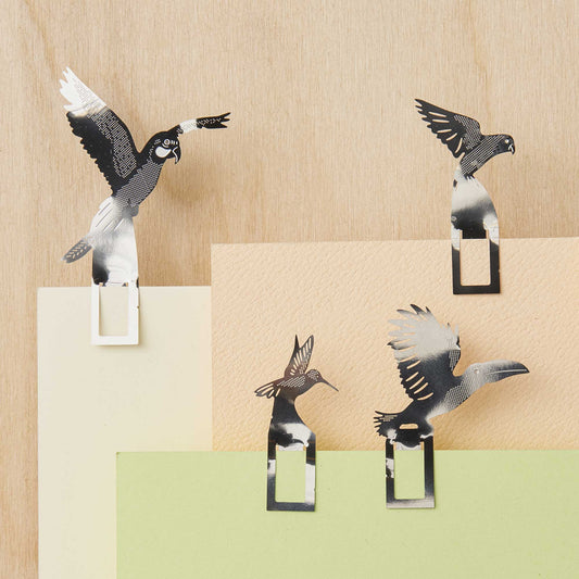 Decorative bird-shaped paper clips on a wooden surface with color swatches.