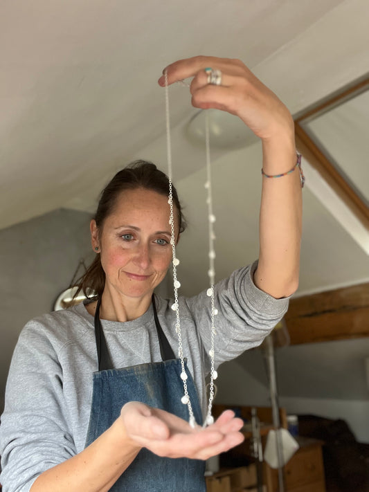 Antonella holding a long silver necklace handmade in her Hebden Bridge studio