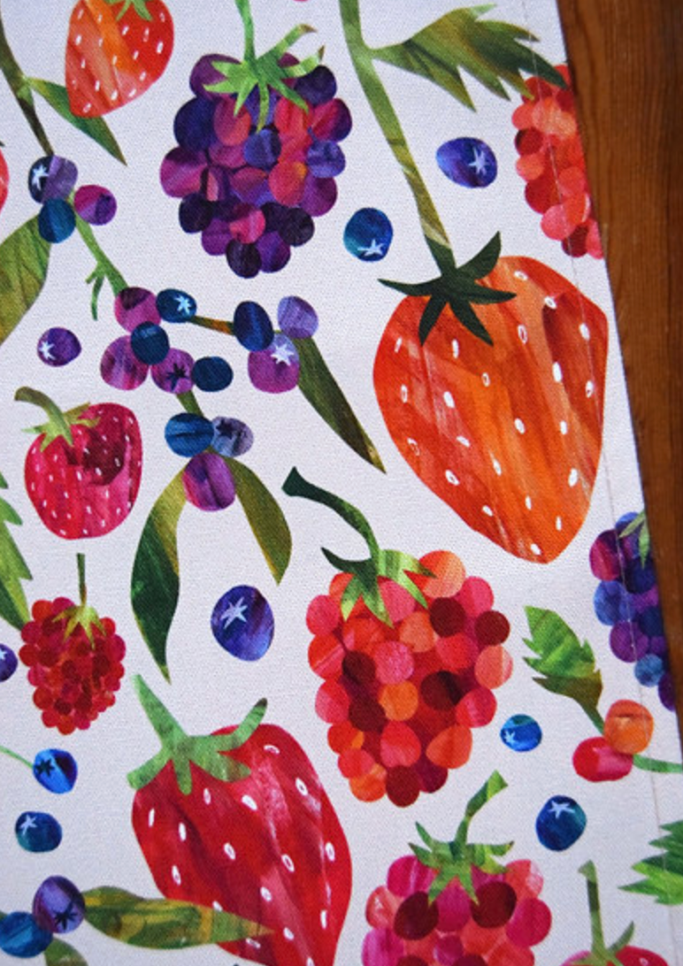 Close up of a tea towel by Freya snow with a colorful illustration of berries on a white background