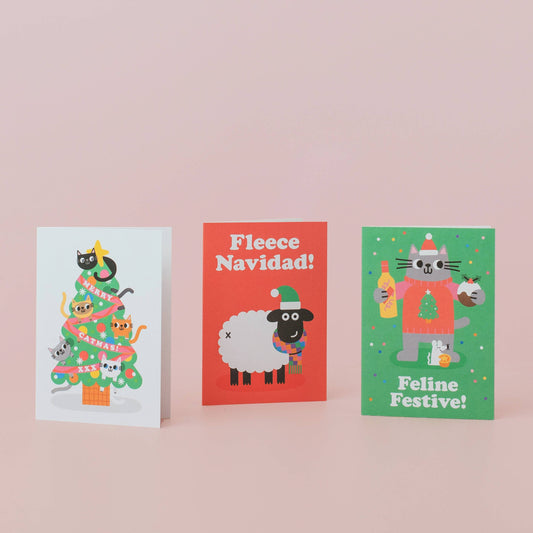 Three festive greeting cards with Christmas-themed illustrations on a pink background.