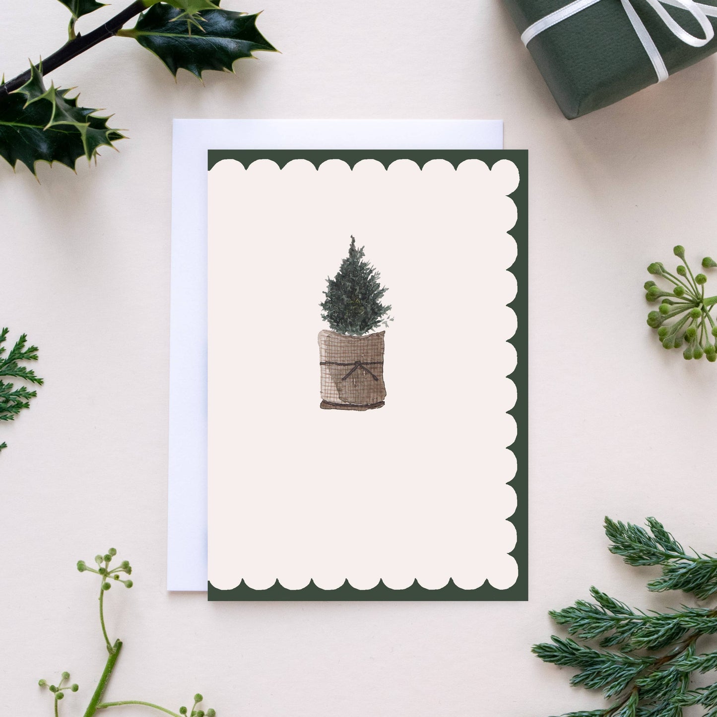 Greeting card with a Christmas tree design on a white background with greenery.