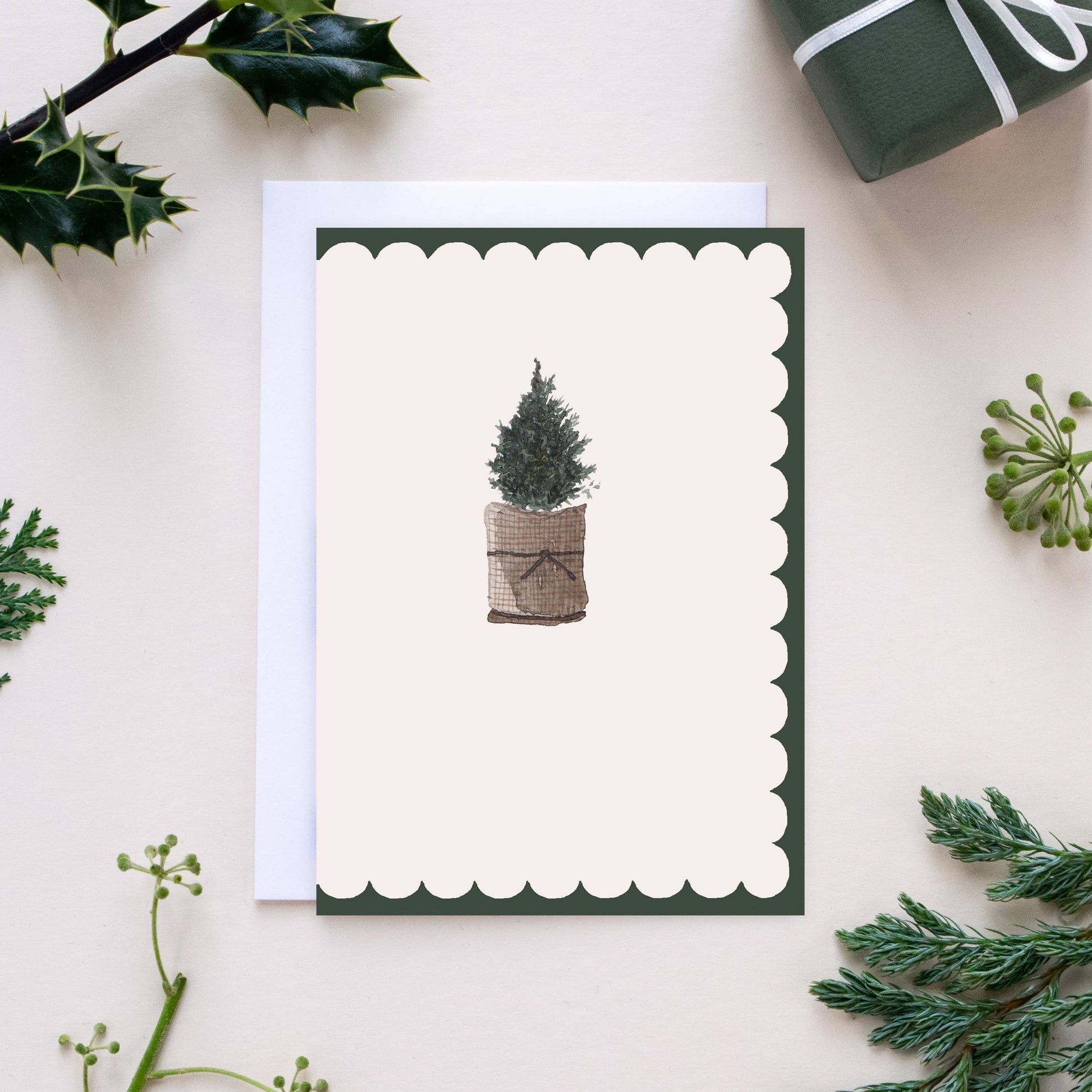 Greeting card with a Christmas tree design on a white background with greenery.