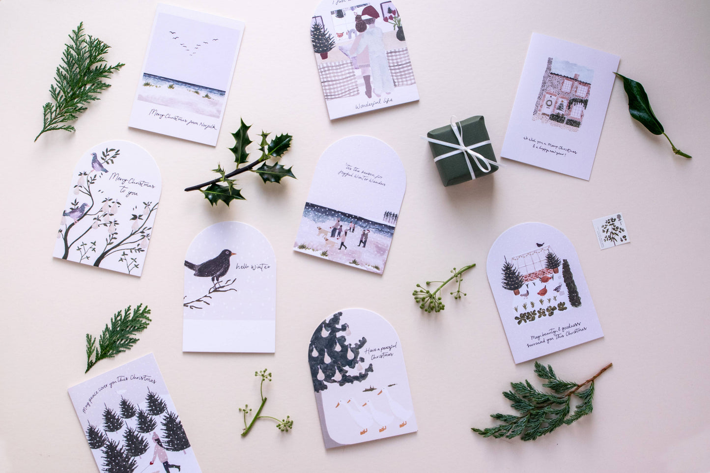 Set of greeting cards with nature-themed designs on a light surface with greenery.