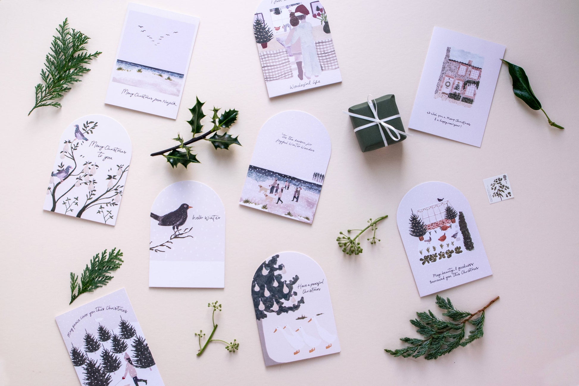 Set of greeting cards with nature-themed designs on a light surface with greenery.