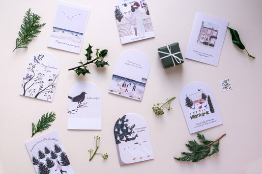 Set of greeting cards with nature-themed designs on a light surface with greenery.