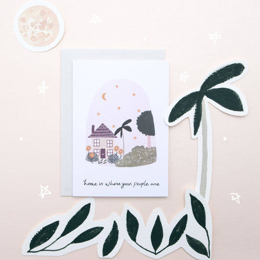 Greeting card with house illustration and decorative stickers on a light pink background