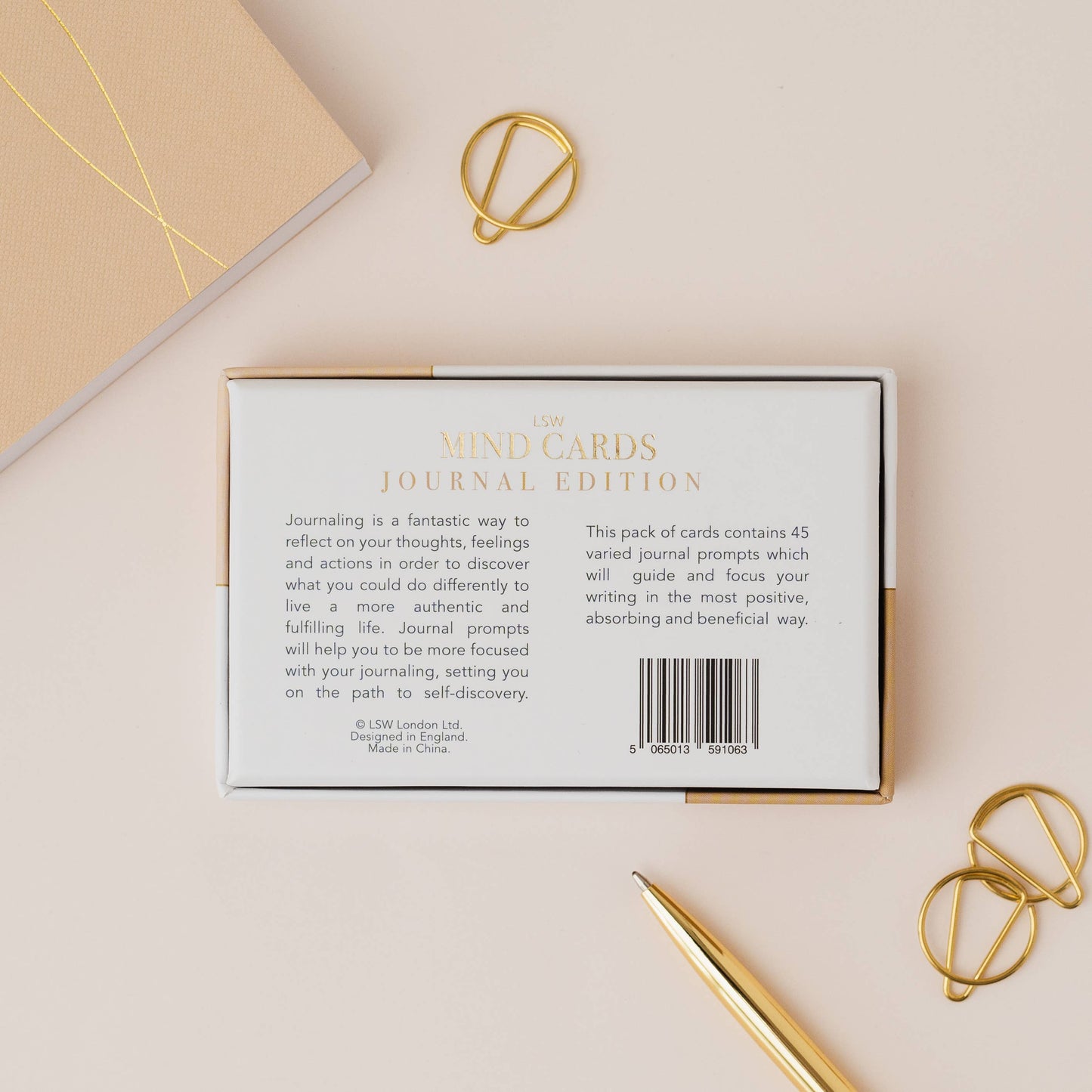 Cardboard box with text and a barcode on a beige surface with gold accents