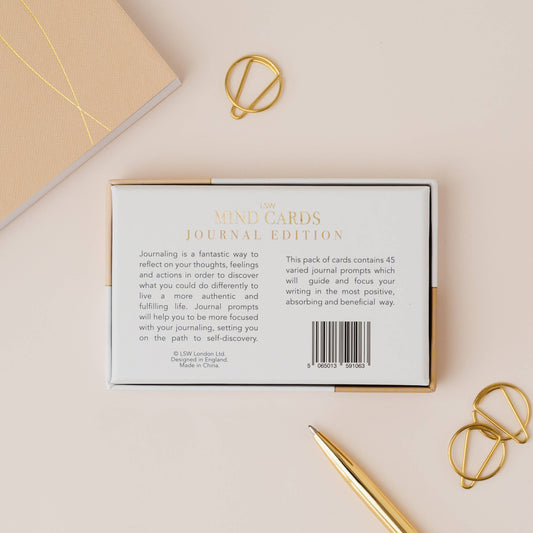Cardboard box with text and a barcode on a beige surface with gold accents