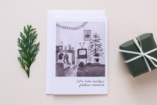 Greeting card with black and white illustration of a living room, greenery, and gift box on a beige background