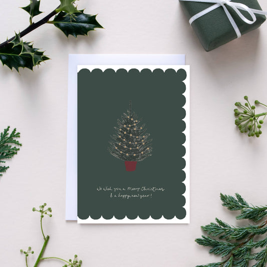 Christmas card with a tree design surrounded by greenery on a light background