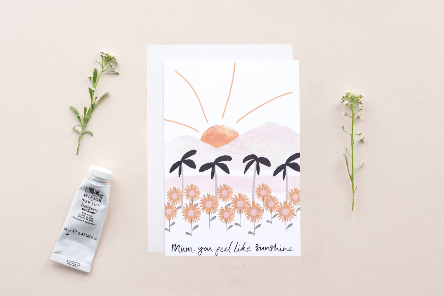 Card with floral design and text, placed on a beige surface with decorative elements.