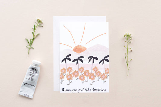 Card with floral design and text, placed on a beige surface with decorative elements.