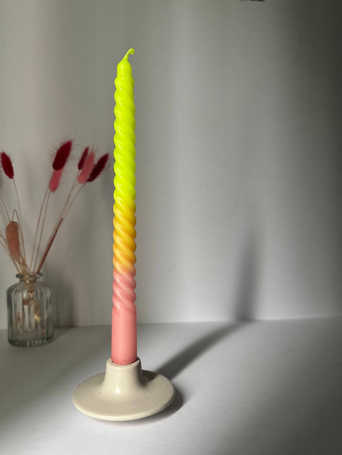 Colorful twisted candle on a white stand with a plain background