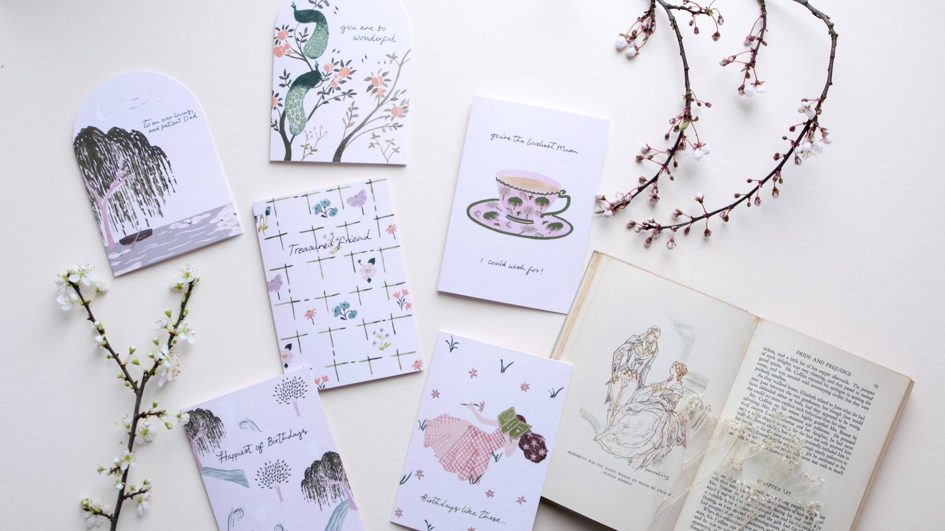 Collection of greeting cards with illustrations on a white surface with floral branches.