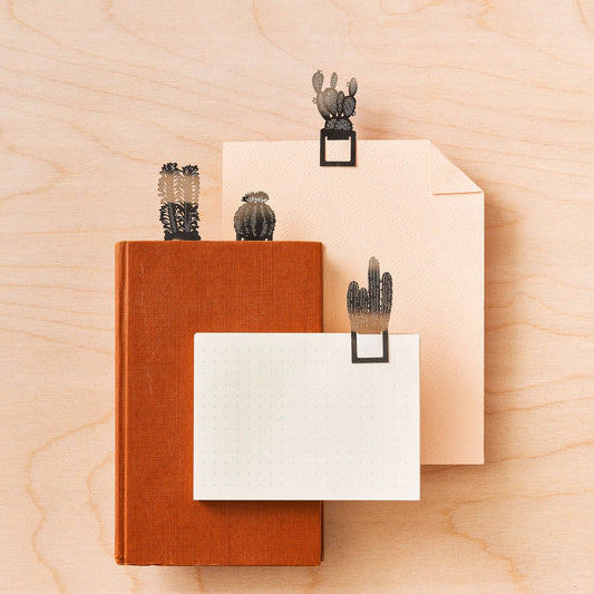 A set of four metal cactus-shaped bookmarks in silver colour styled with books and paper