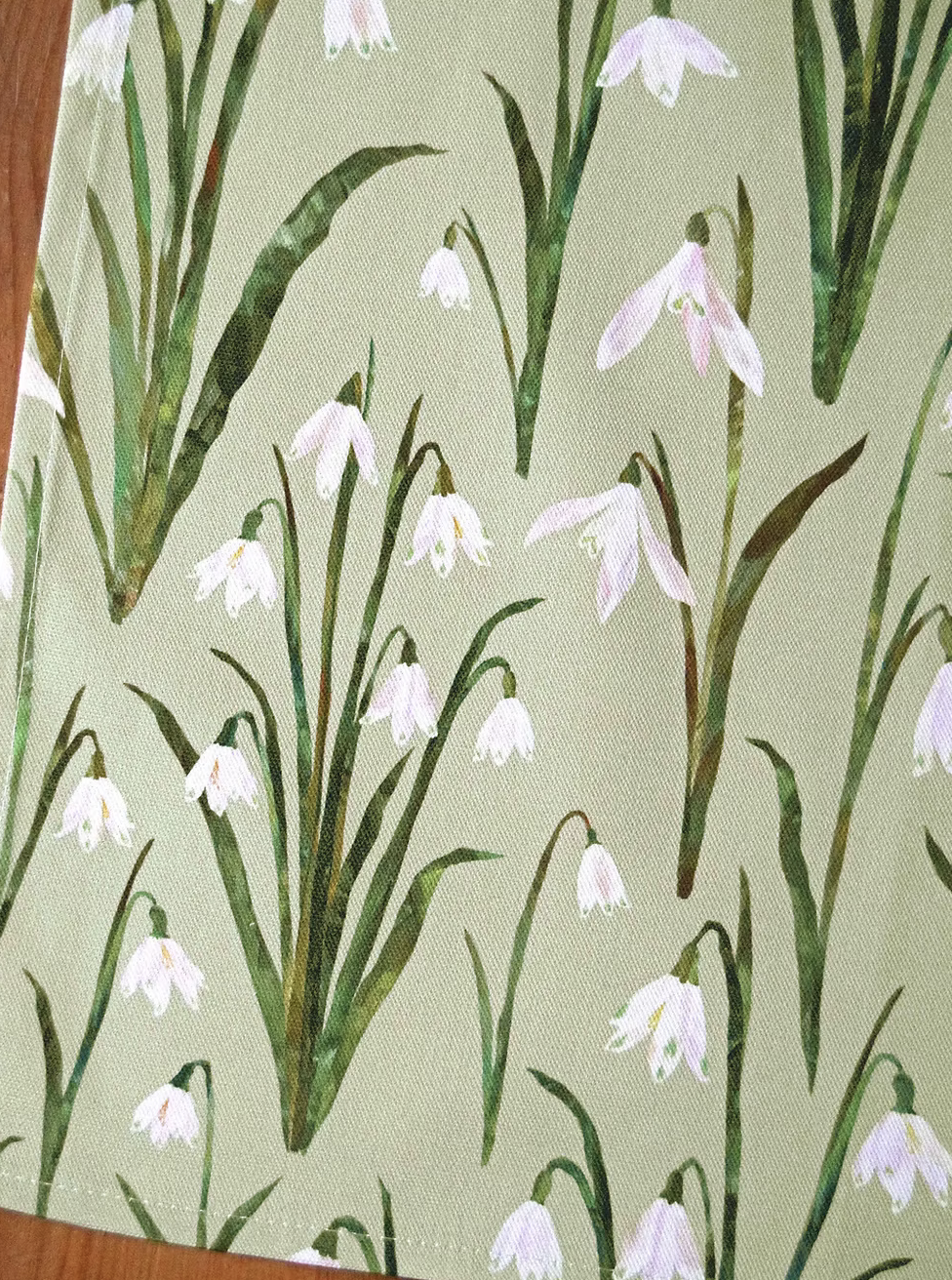 close up of snowdrops tea towel by Freya Snow on a light green background