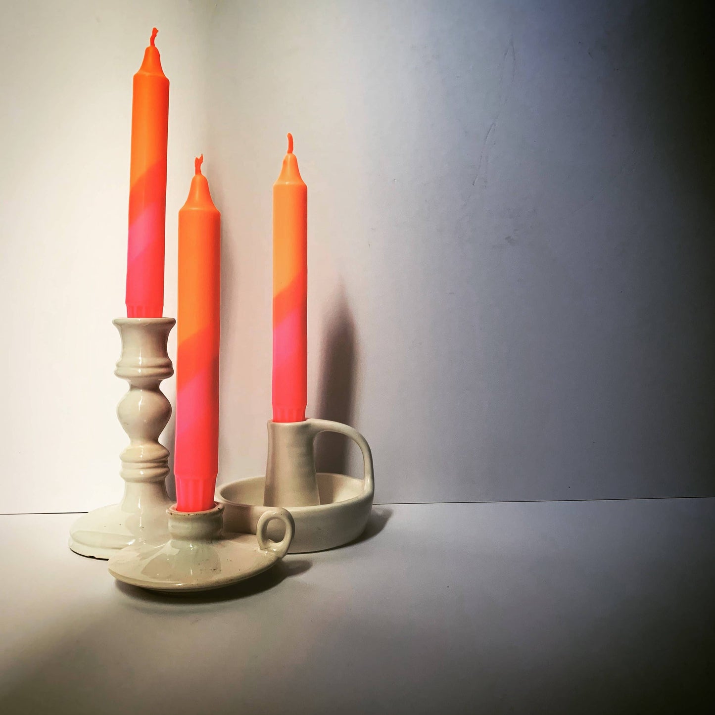 Three orange candles in ceramic holders on a plain background hand dip dyed by The Singing Rabbit