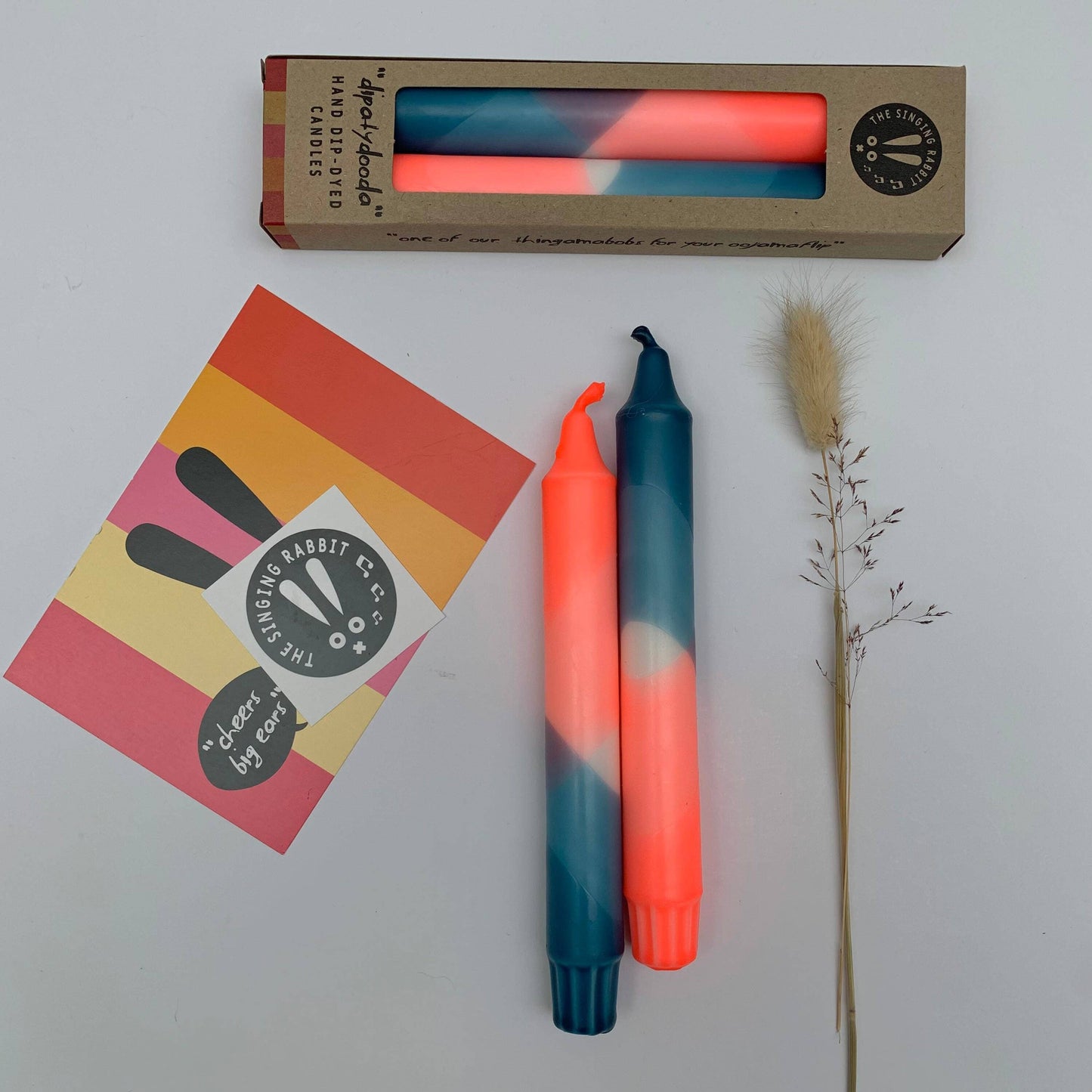 Two colorful candles with a box and card on a light grey background by The Singing Rabbit for Heart Gallery