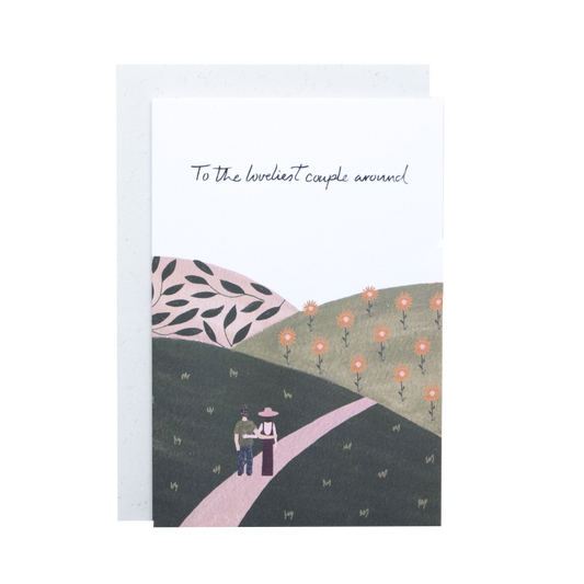 Greeting card with illustration of a couple walking on a path with flowers, text 'To the loveliest couple around'.