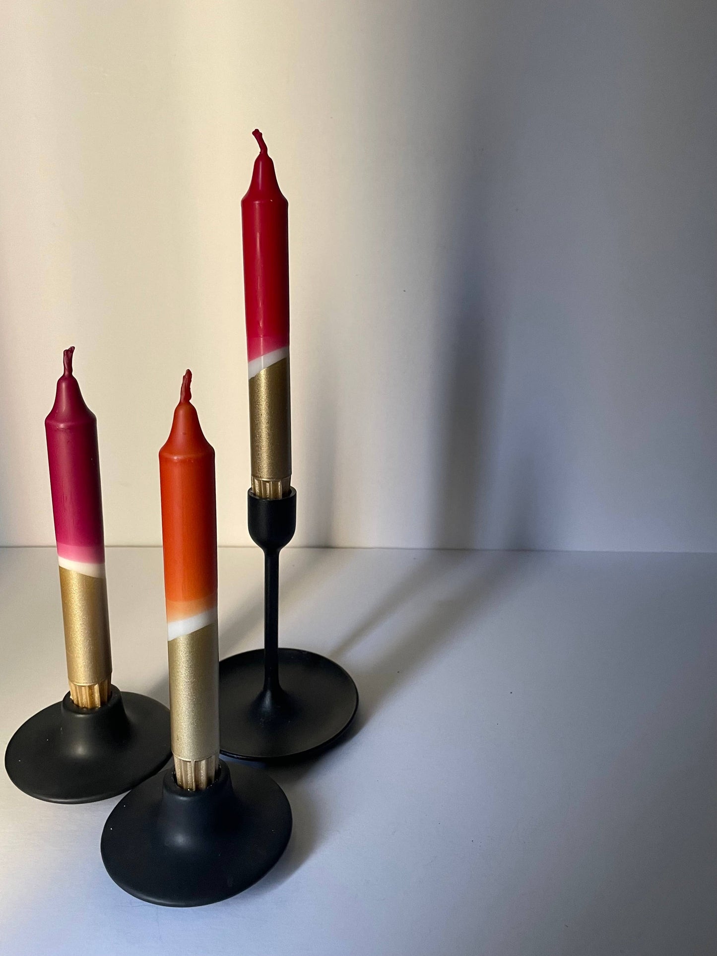 Three candles with gradient colors on black stands against a plain background styled for Heart Gallery by The Singing Rabbit