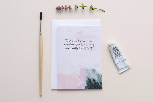 card with a motivational quote, paintbrush, and tube of paint on a light background