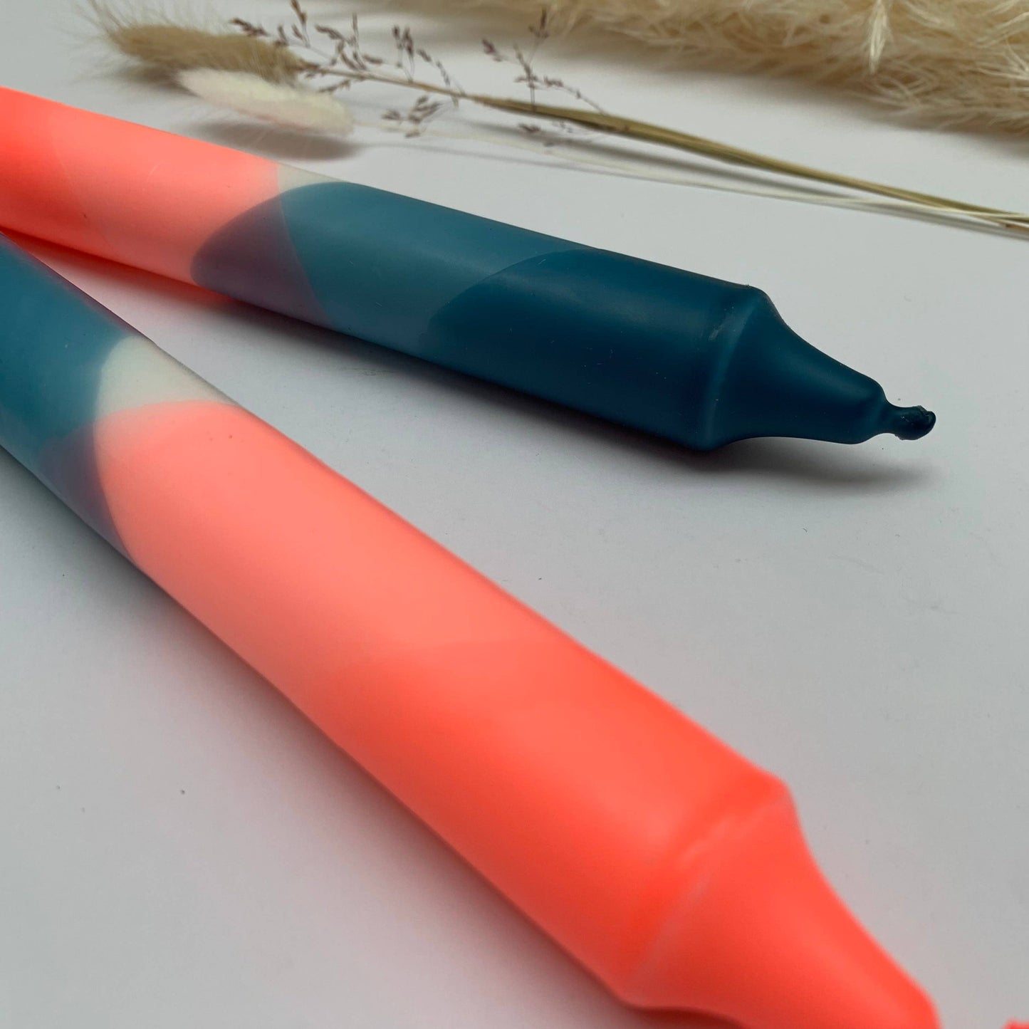 Two hand-dip-dyed candles in neon coral and teal blue by The Singing Rabbit