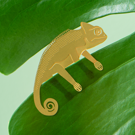 Gold coloured chameleon figurine on a green leaf