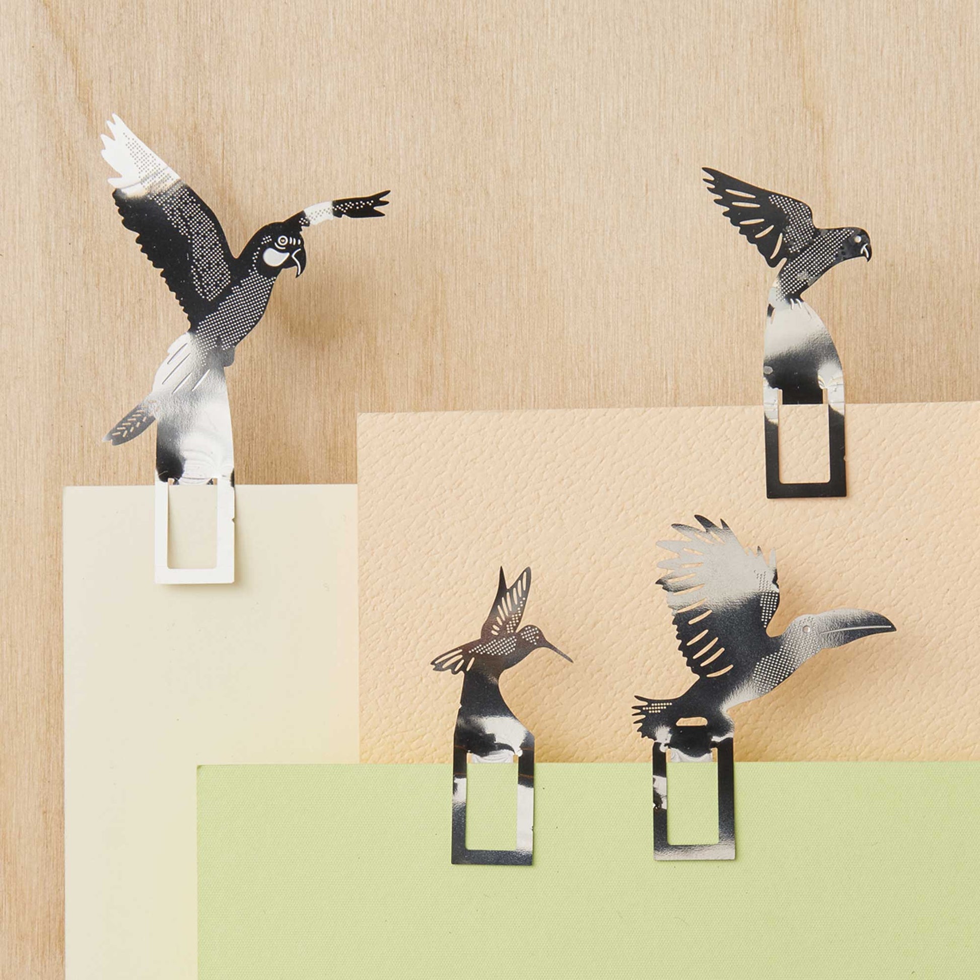 Decorative bird-shaped paper clips on a wooden surface with color swatches.