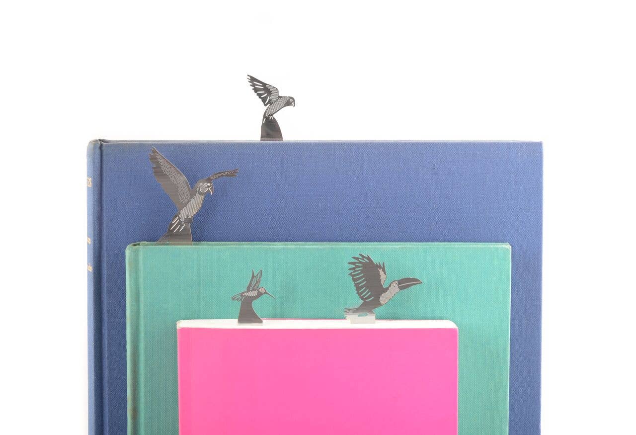 Metal bird bookmarks on a stack of books with a white background