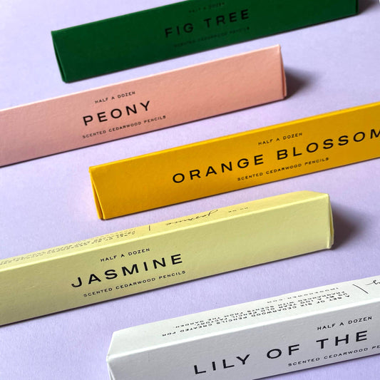 Colorful boxes of scented cedarwood pencils on a light purple background by Imogen owen for Heart Gallery