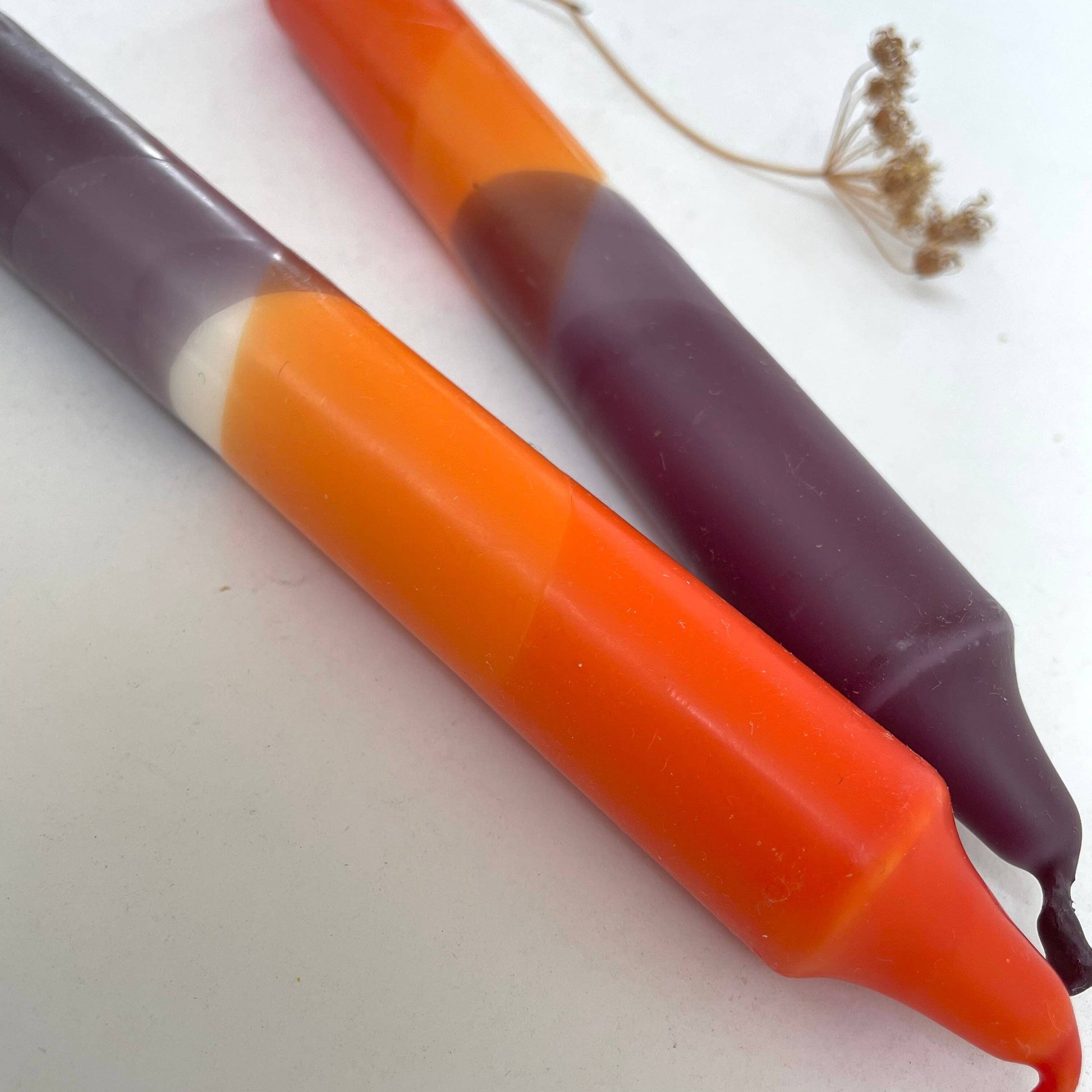 Close up of two candles by The Singing Rabbit hand dip dyed in aubergine and rust red