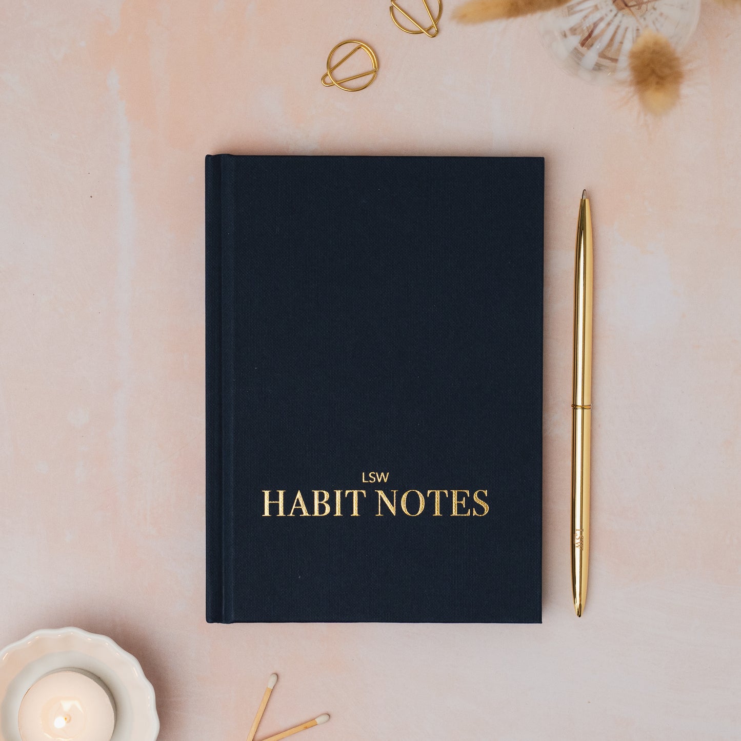 Dark Blue  notebook titled 'Habit Notes' with a gold pen on a decorative surface. LSW Habit Notes