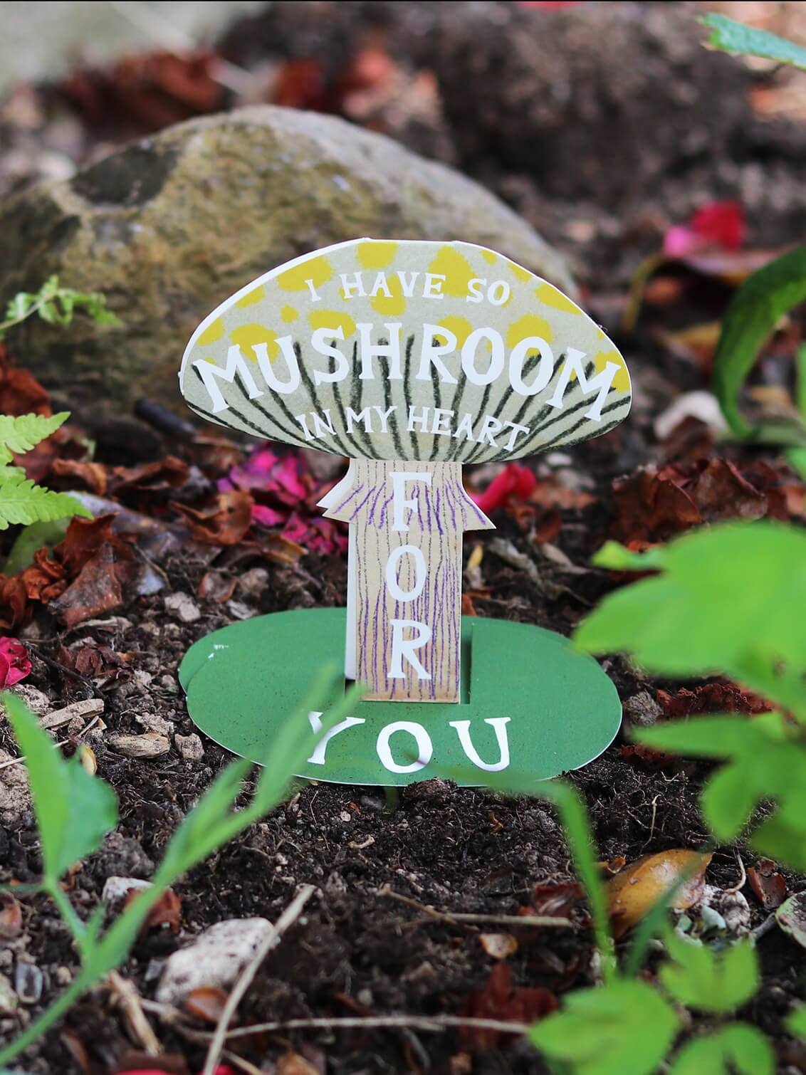Mushroom-shaped sign with text in a garden setting