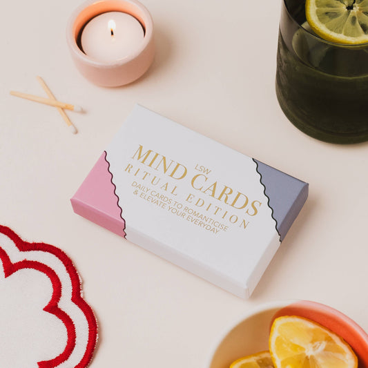 Box of 'Mind Cards Ritual Edition' on a table with a candle and lemon slices.