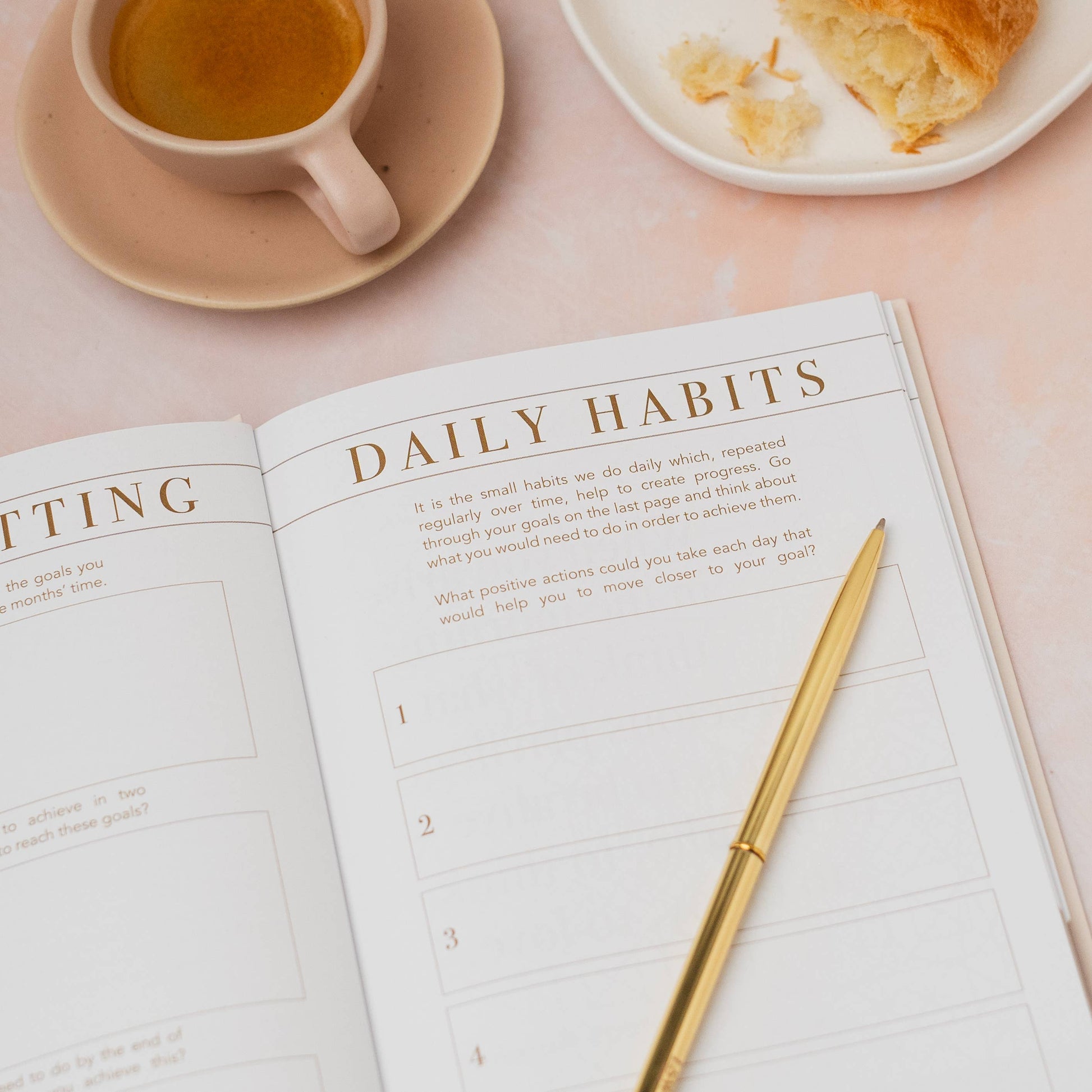 Open planner with 'Daily Habits' section on a table with a cup of tea and bread.