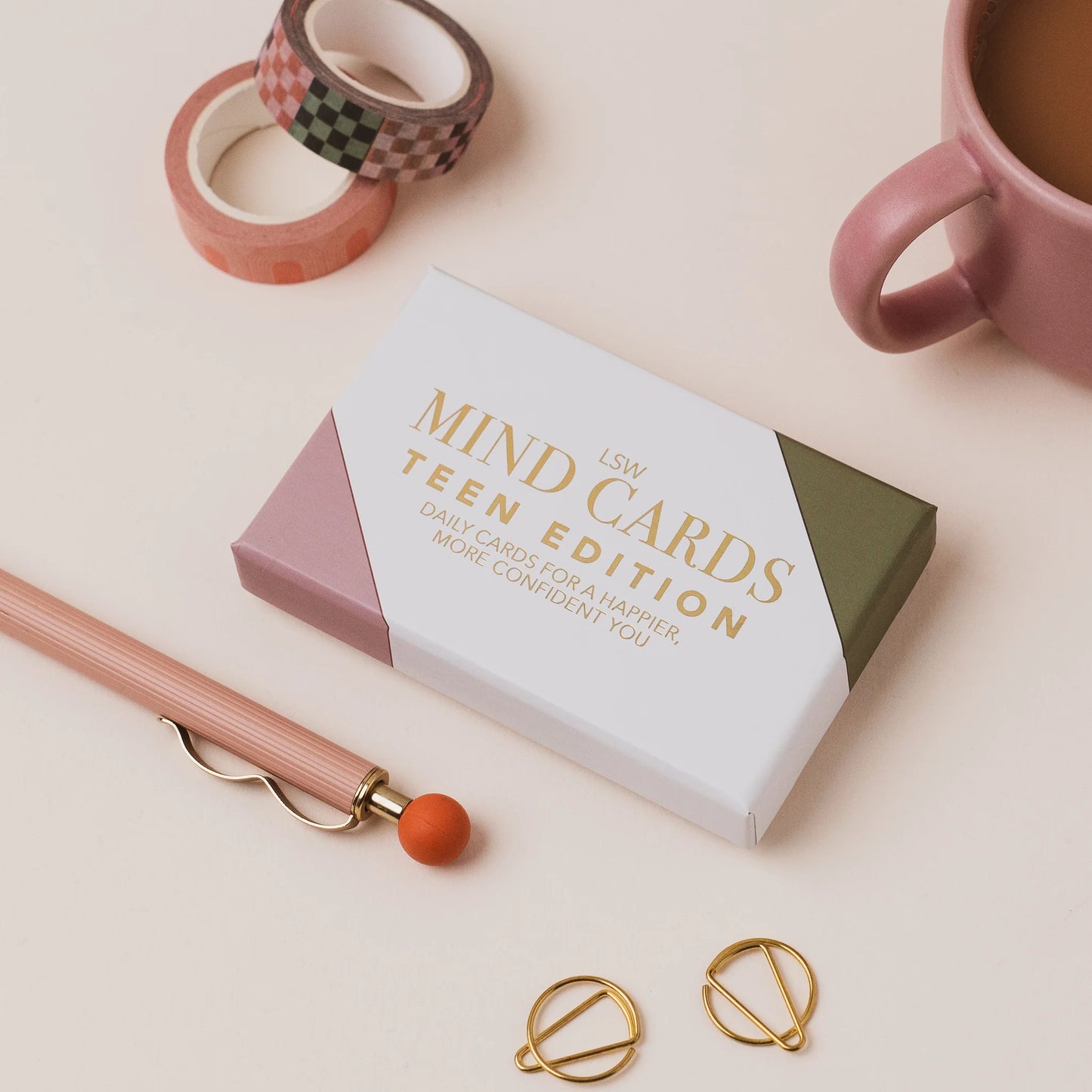 Box of 'MIND CARDS Teen Edition' on a light surface with a pink mug, pencil, and decorative items.