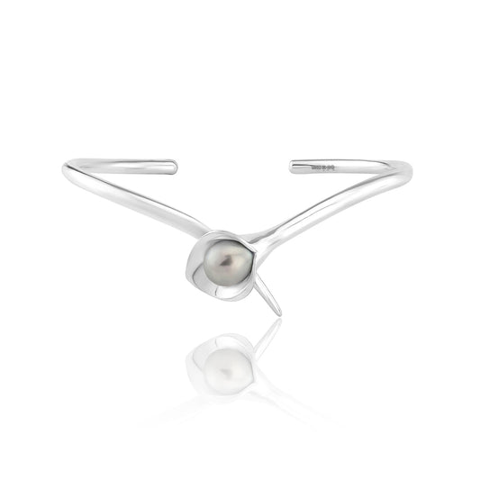 A silver bangle bracelet with a large cultured freshwater pearl, displayed against a white background.Amanda Cox, jewellery handmade in Hebden Bridge Yorkshire for Heart Gallery