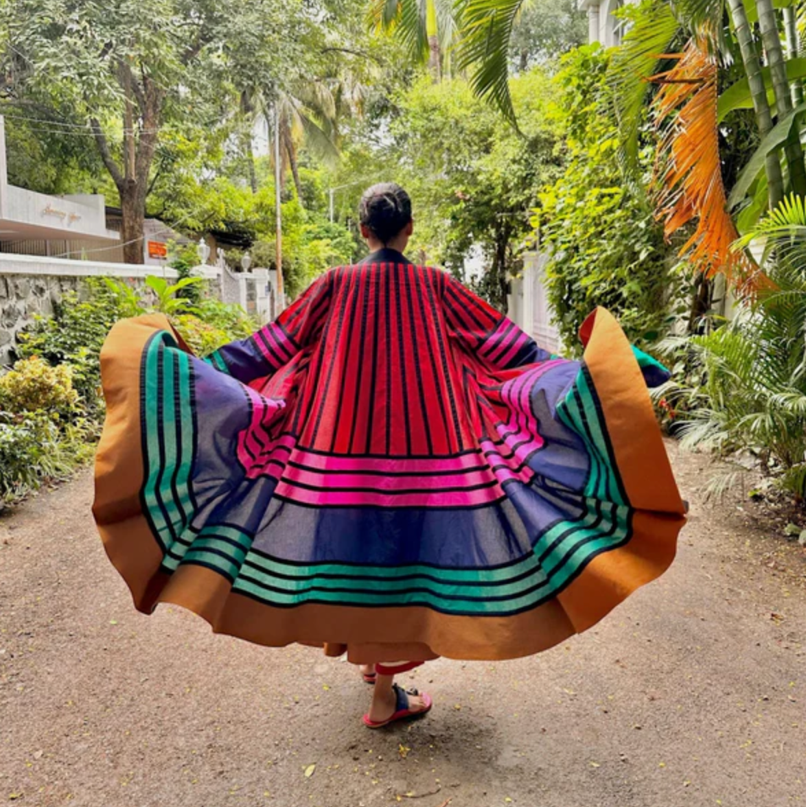 Person wearing a colorful, patterned dress walking in a garden setting