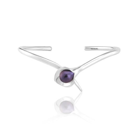 A silver bangle bracelet with a large cultured freshwater pearl, displayed against a white background.Amanda Cox, jewellery handmade in Hebden Bridge Yorkshire for Heart Gallery