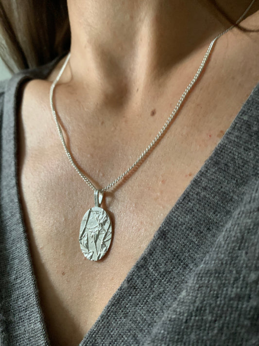 Silver necklace with a round pendant on Antonella's  neck. Jewellery workshop at Heart Gallery Hebden Bridge West Yorkshire
