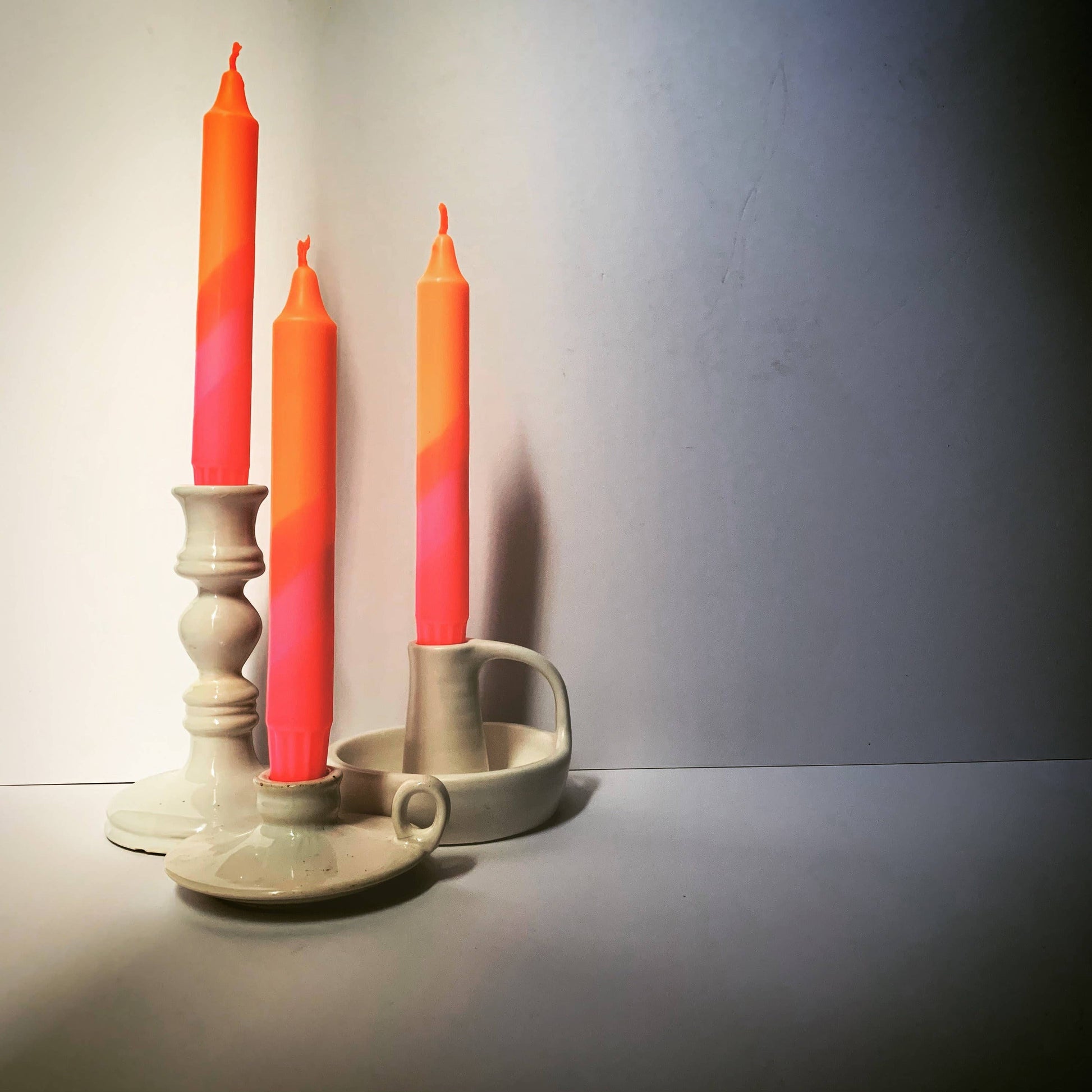 Three orange candles in ceramic holders on a plain background hand dip dyed by The Singing Rabbit