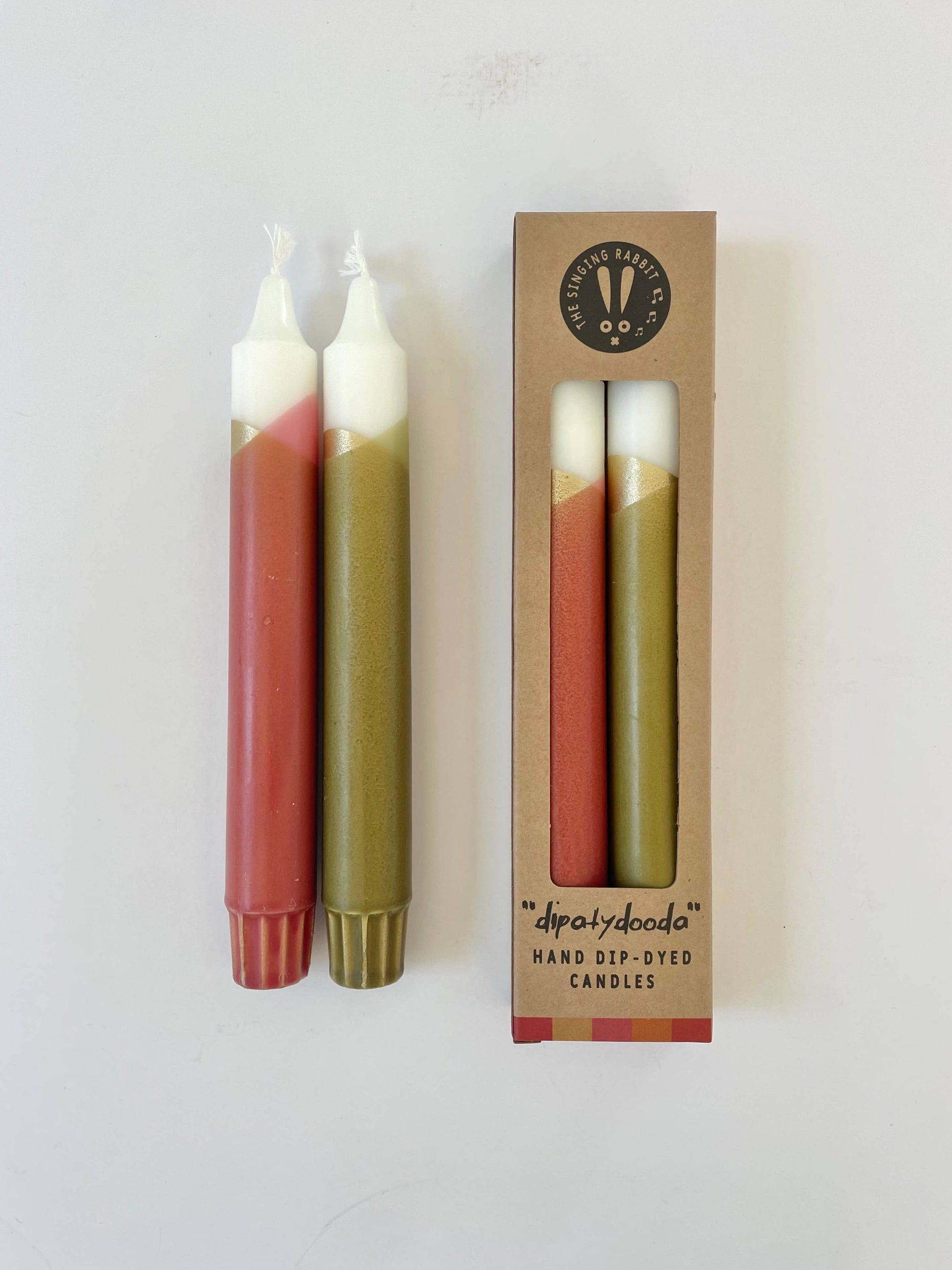 Two candles with a gradient color pattern and their packaging on a white background.