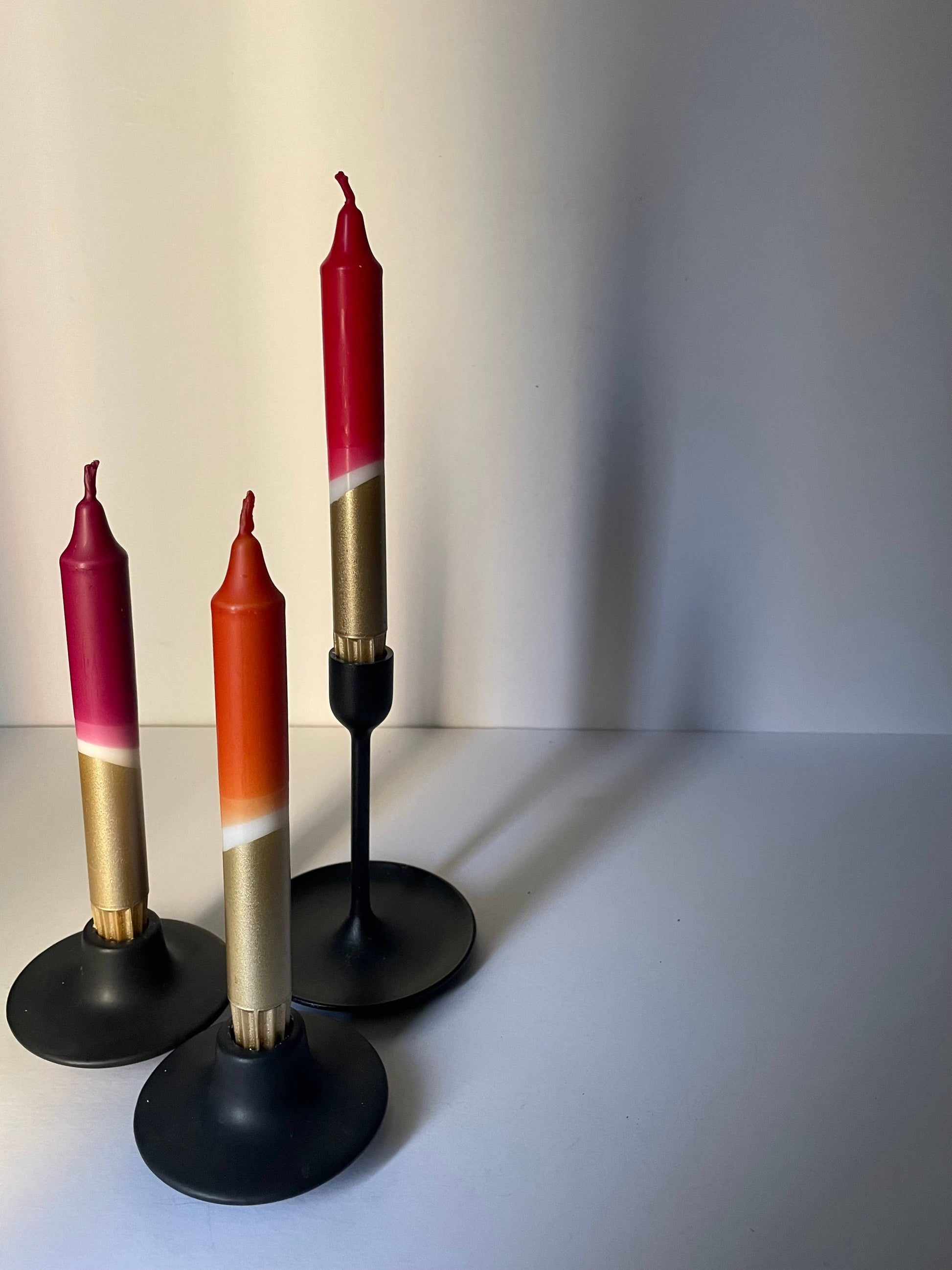 Three candles with gradient colors on black stands against a plain background styled for Heart Gallery by The Singing Rabbit