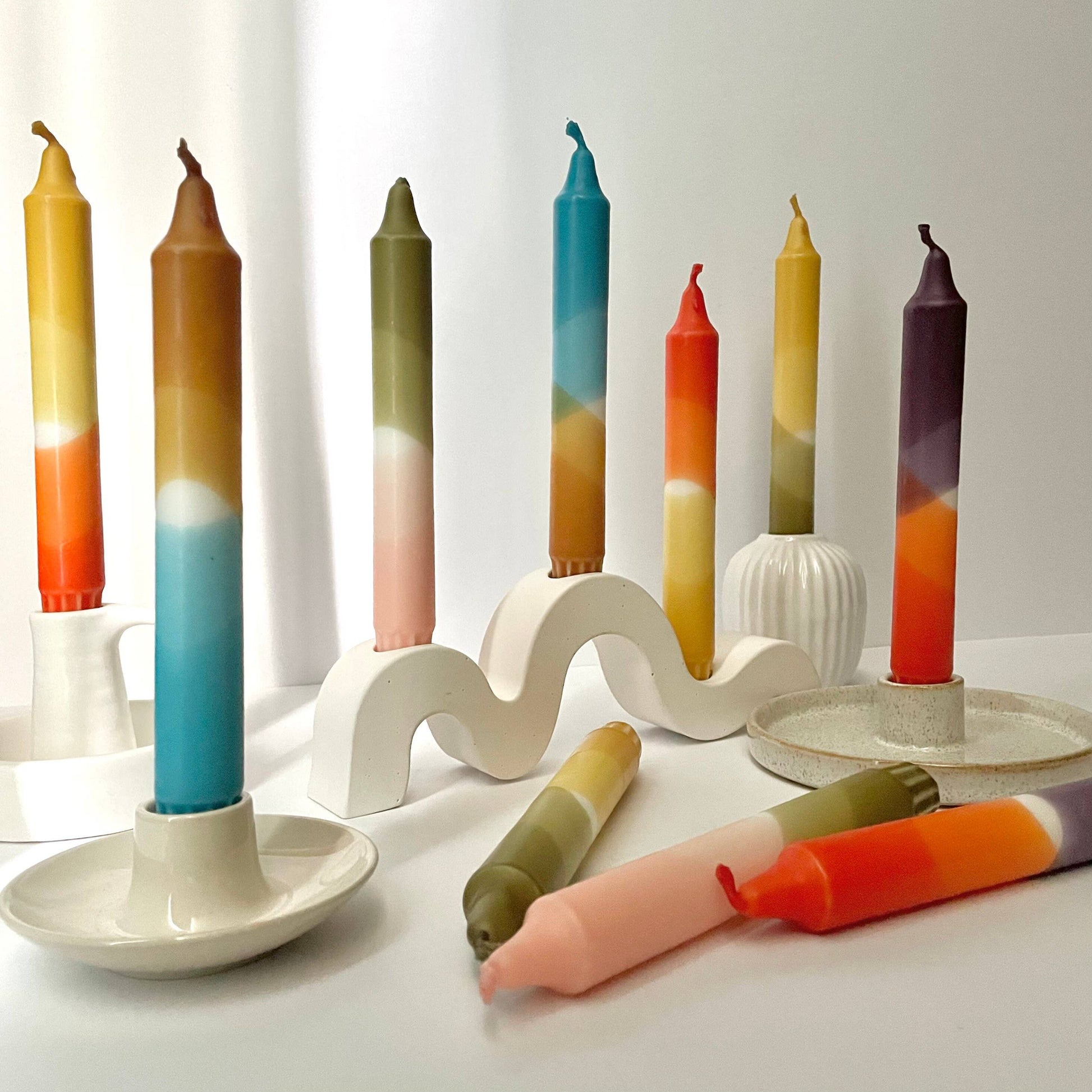 Set of colorful candles with a wavy candle holder on a white background