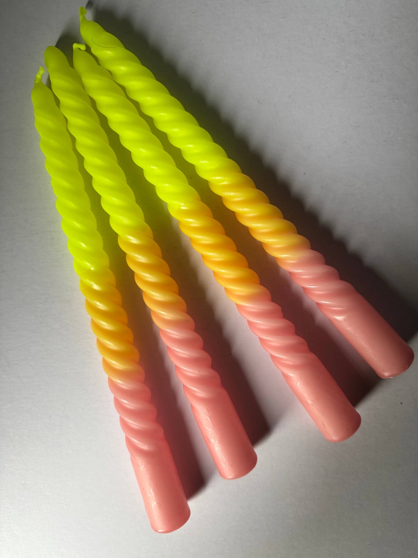 Four colorful twisted candles on a gray background
