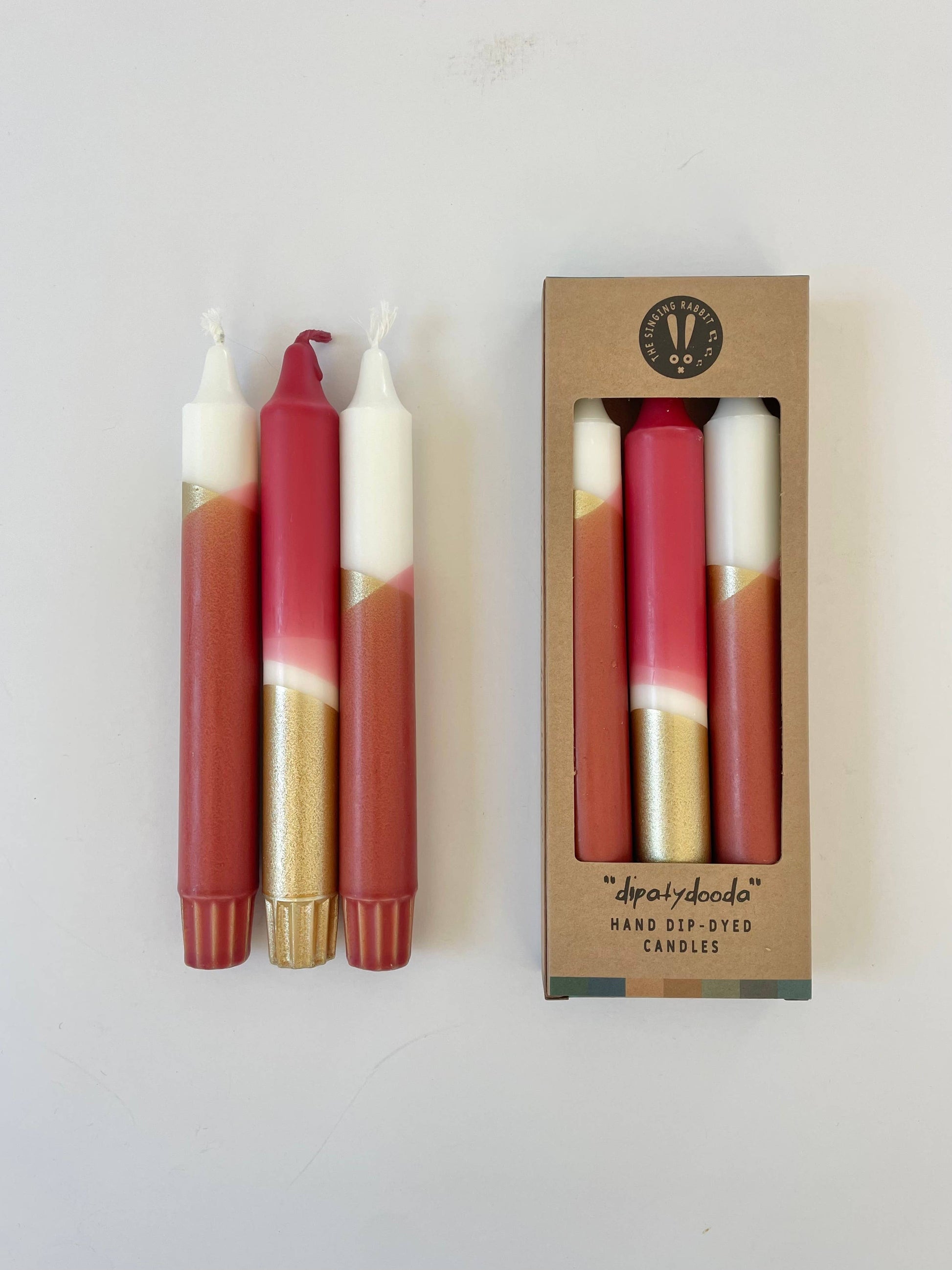 Set of dip-dyed candles with a matching box on a white background