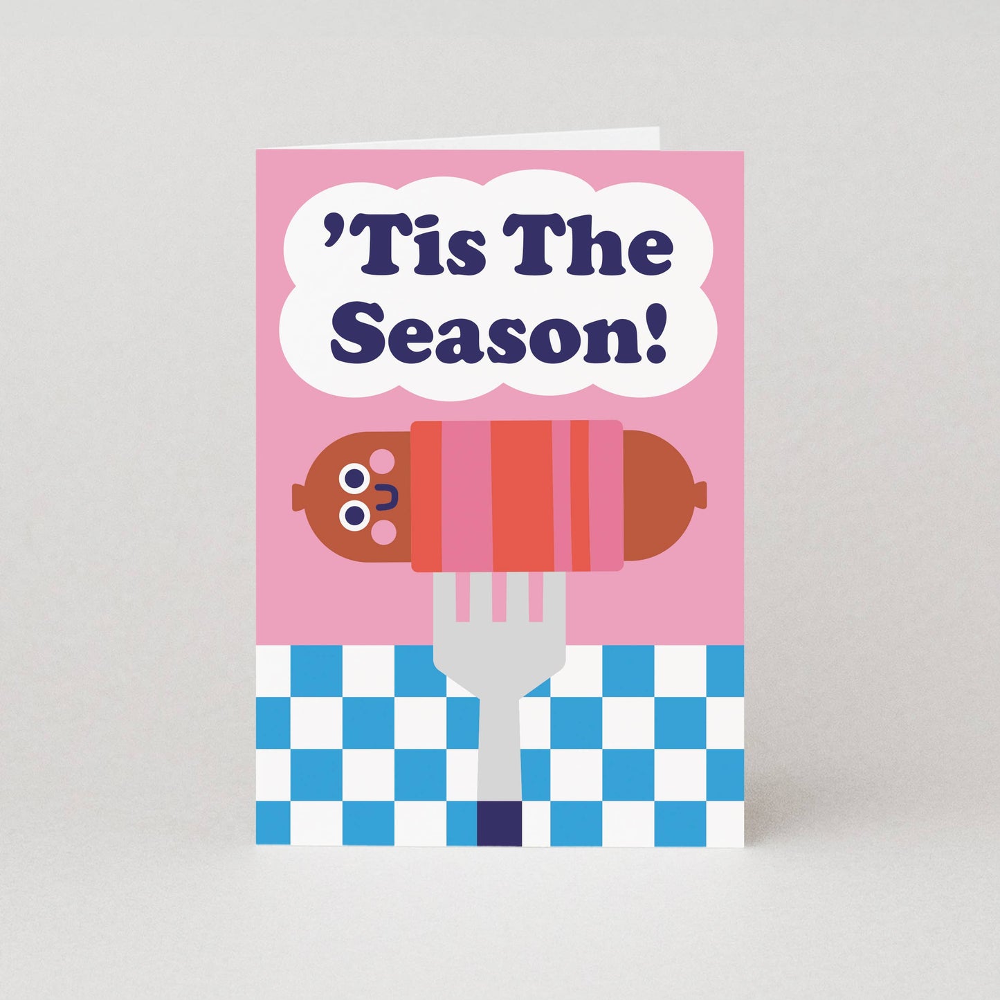 Card with a cartoon hot dog on a fork and 'Tis The Season text on a pink background