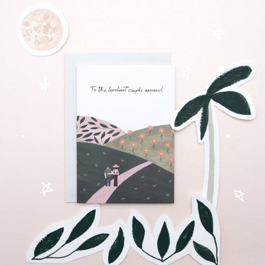 Greeting card with a couple and palm tree design on a pink background