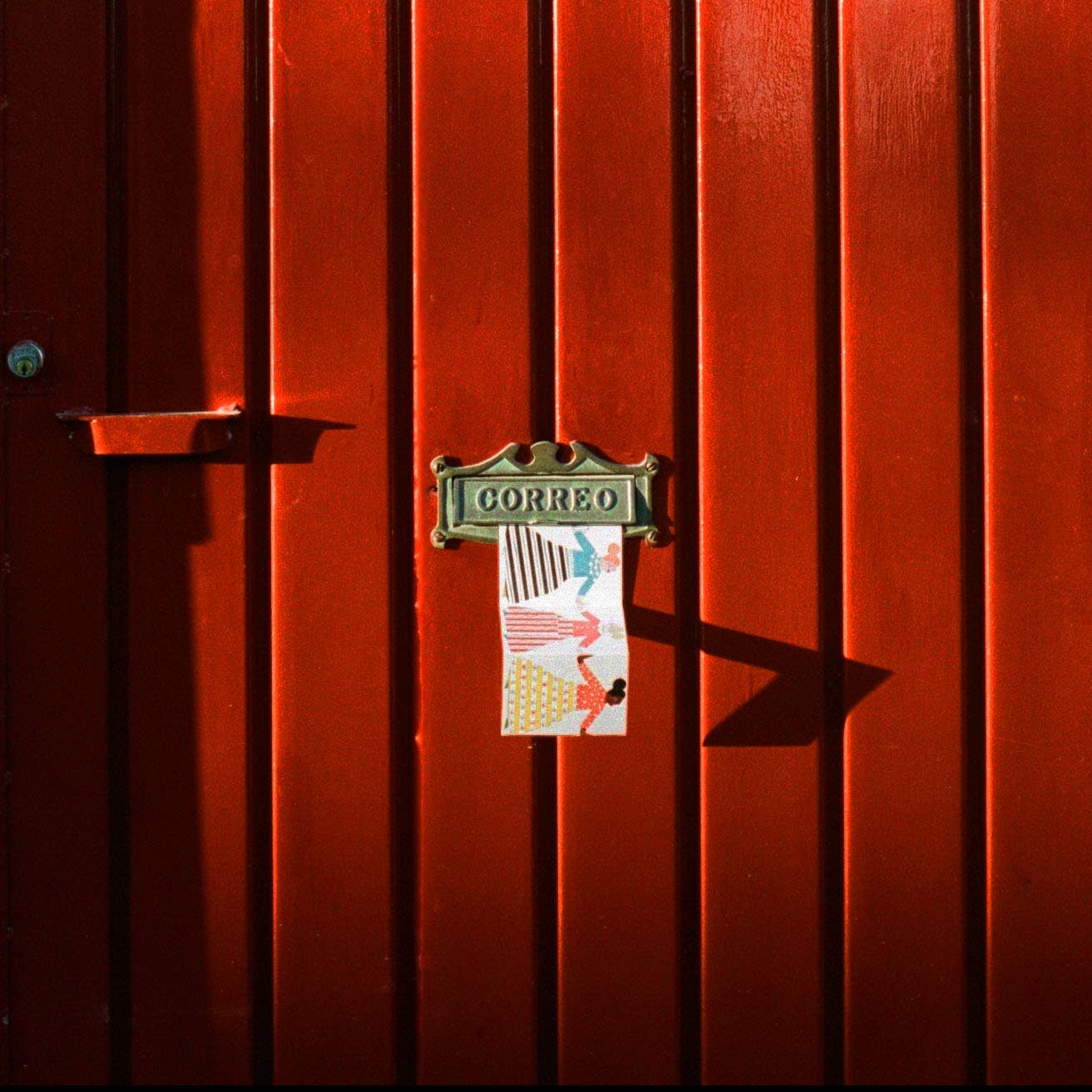 Red door with a 'Correo' mailbox and a concertina ard bein posted through it